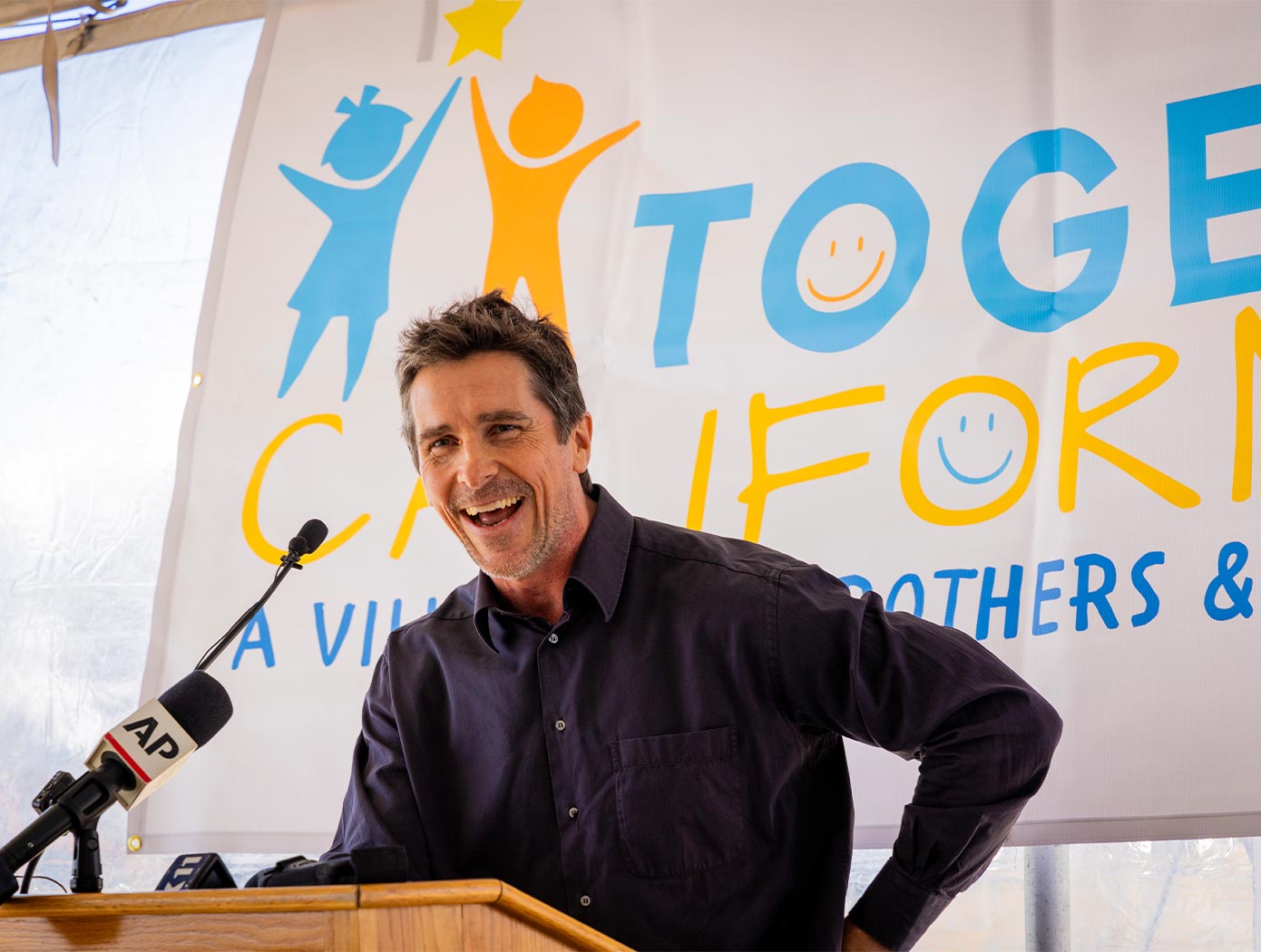 A man standing at a podium smiling, giving a speech as an event opener. 